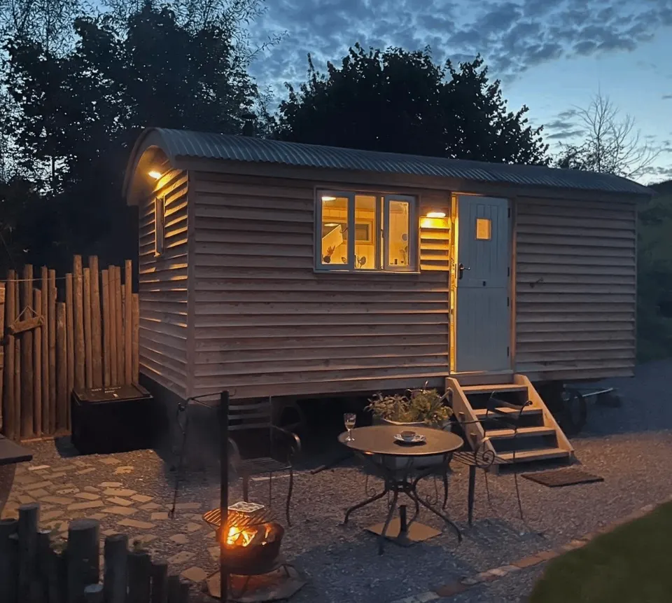 Glamping hut with warm interior lighting at dusk